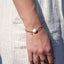Bracelet Célia en acier inoxydable 316L doré avec perle d’eau douce et quartz cristal porté au poignet

