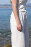 Bracelet Marella en acier inoxydable doré porté avec une tenue blanche au bord de l’eau