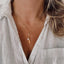 Collier doré en acier inoxydable avec pendentif “Amour” et perles naturelles.